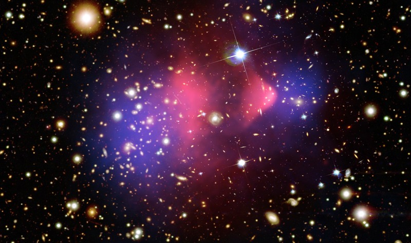 This composite image of the so-called “Bullet Cluster” is strong evidence for the existence of dark matter. (Image: X-ray: NASA/CXC/CfA/ M.Markevitch et al.; Lensing Map: NASA/STScI; ESO WFI; Magellan/U.Arizona/; D.Clowe et al.; Optical: NASA/STScI; Magellan/U.Arizona/D.Clowe et al.